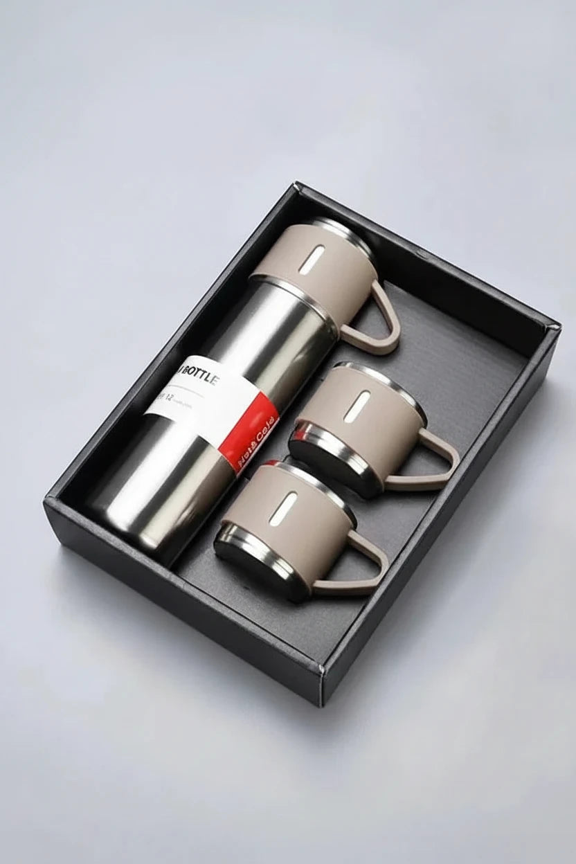 A stainless steel vacuum flask bottle with two matching ceramic cups presented in a black gift box. The bottle has a silver metallic body with a beige handle and collar, and a white and red paper label.