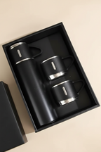 A 4-piece black vacuum insulated mug set in a black gift box, including one 500ml bottle and three matching mugs with silver metal rims.