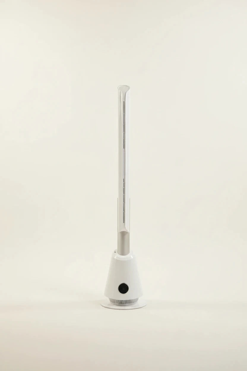 White bladeless tower fan standing on a grey floor in a home office, beside a desk and window