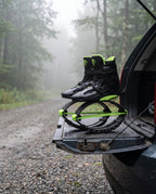 Black and green bounce jump shoes resting on a car tailgate at a misty gravel trailhead
