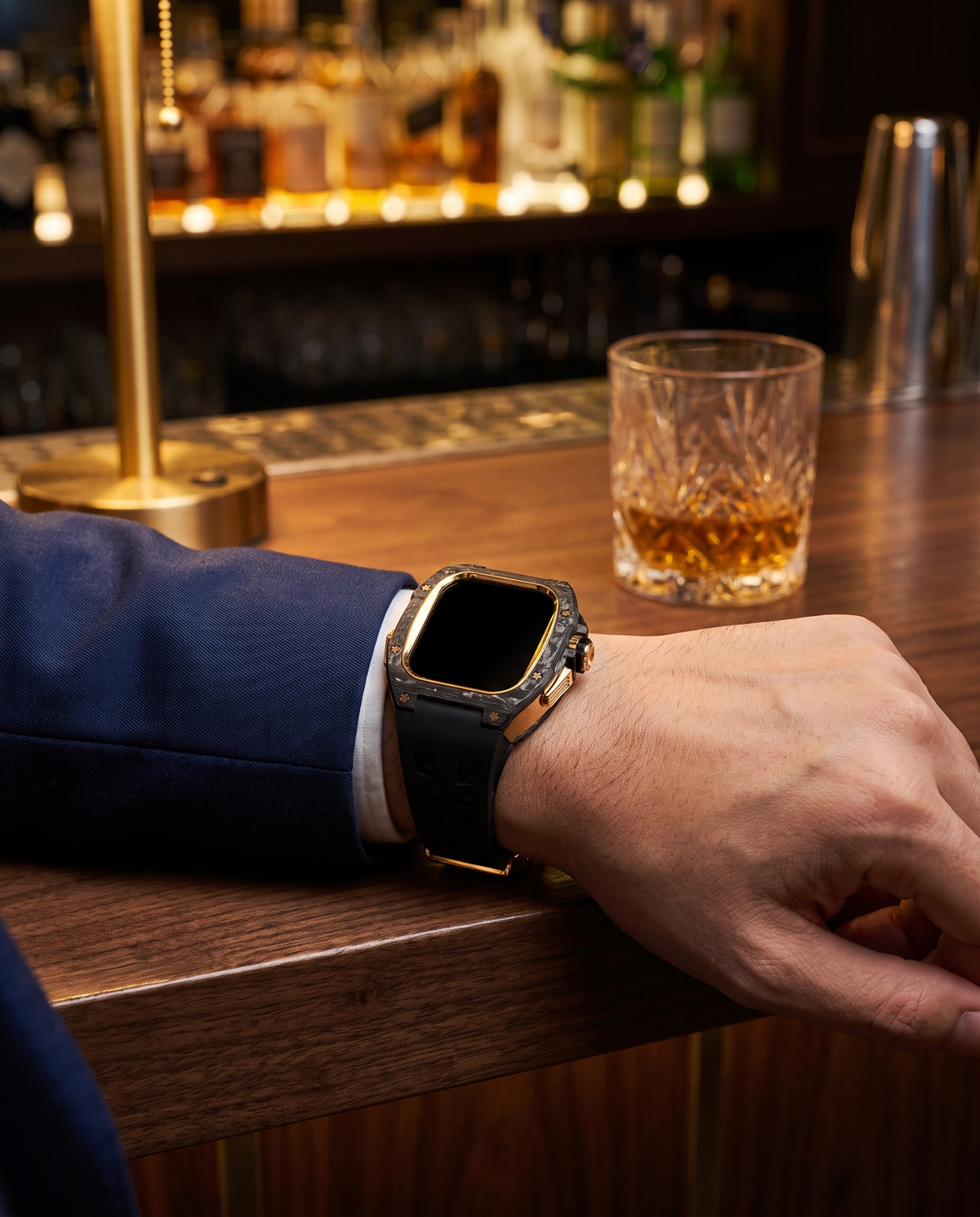 Man in a navy suit wearing the case kit on a black strap, forearm resting on a walnut bar counter