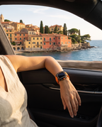 Woman wearing the case kit on an orange strap, arm resting on the open window of a car above a Mediterranean harbour