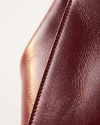 Macro close-up of wine red full grain leather grain texture and edge stitching
