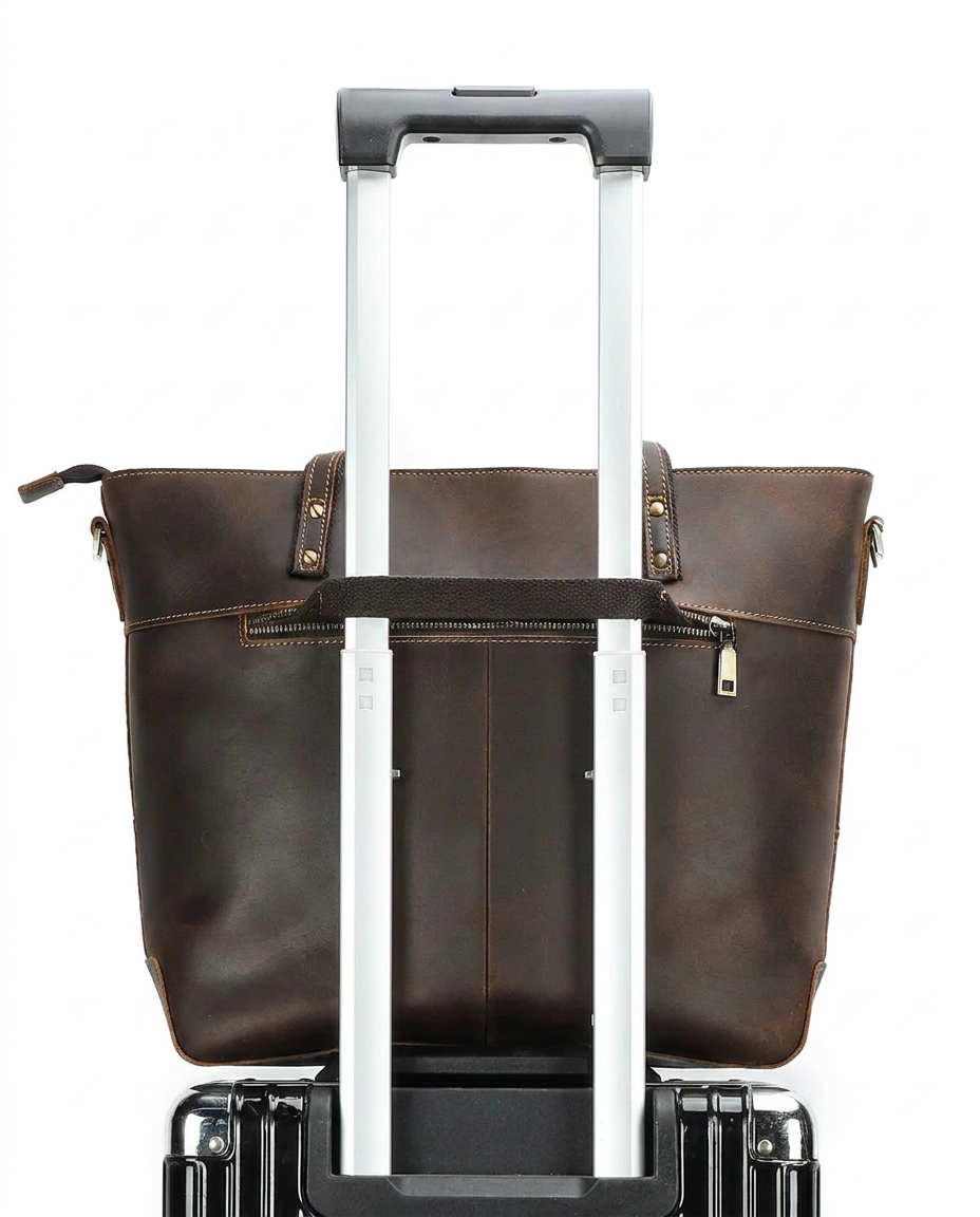 The tote's front zip pocket, shown with a rolling suitcase handle passed through the luggage strap