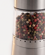 Close view of a mill's clear chamber filled with black, red, green and cream peppercorns