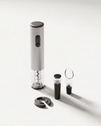 Four-piece electric wine opener gift set in light grey — corkscrew, foil cutter, vacuum stopper and aerator pourer on a soft white studio background