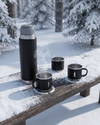 The flask set on a snow-dusted timber bench in a winter pine wood, steam rising from a cup