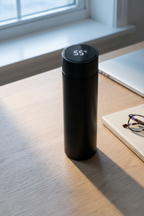 The LED thermos cup on a pale oak desk in early morning light, display lit
