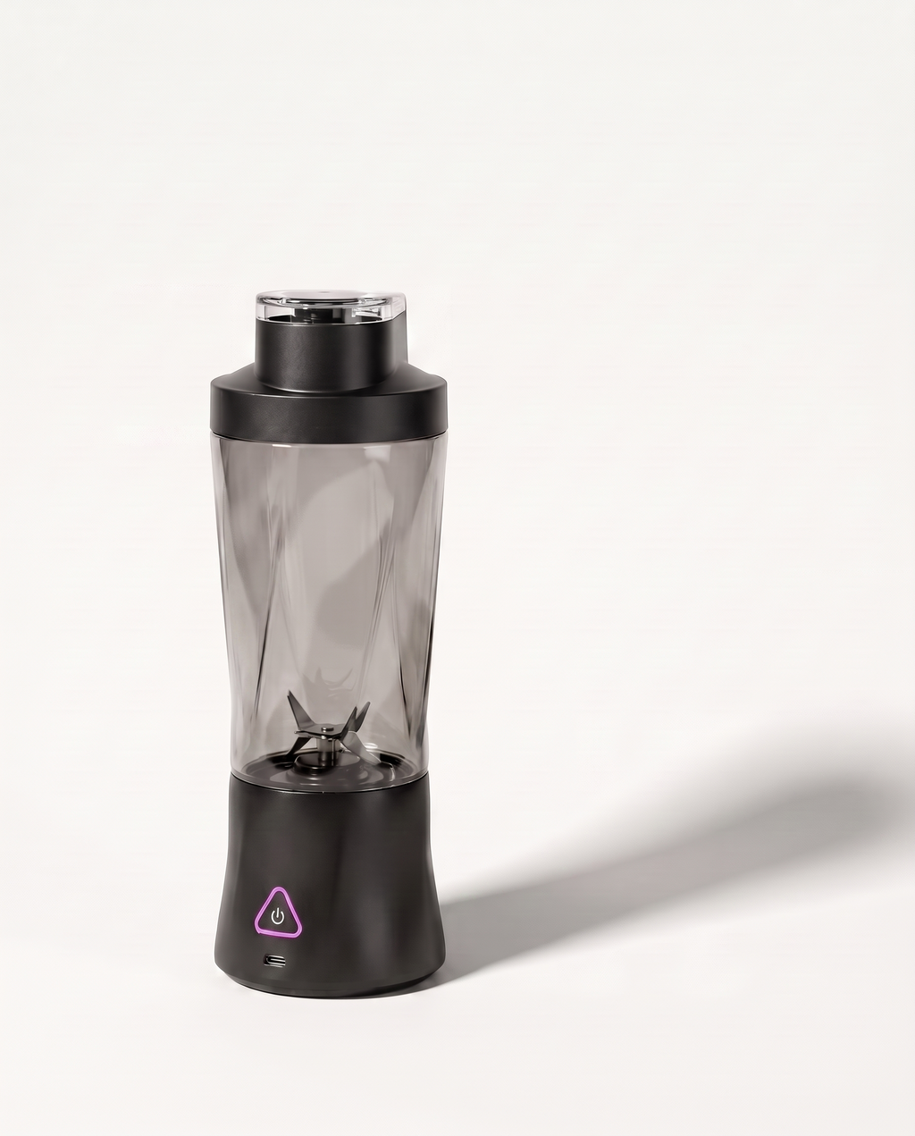 Portable blender in black with a clear tinted 700 ml bottle, six-blade assembly visible through the wall, on a soft white background