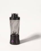 Portable blender in black with a clear tinted 700 ml bottle, six-blade assembly visible through the wall, on a soft white background