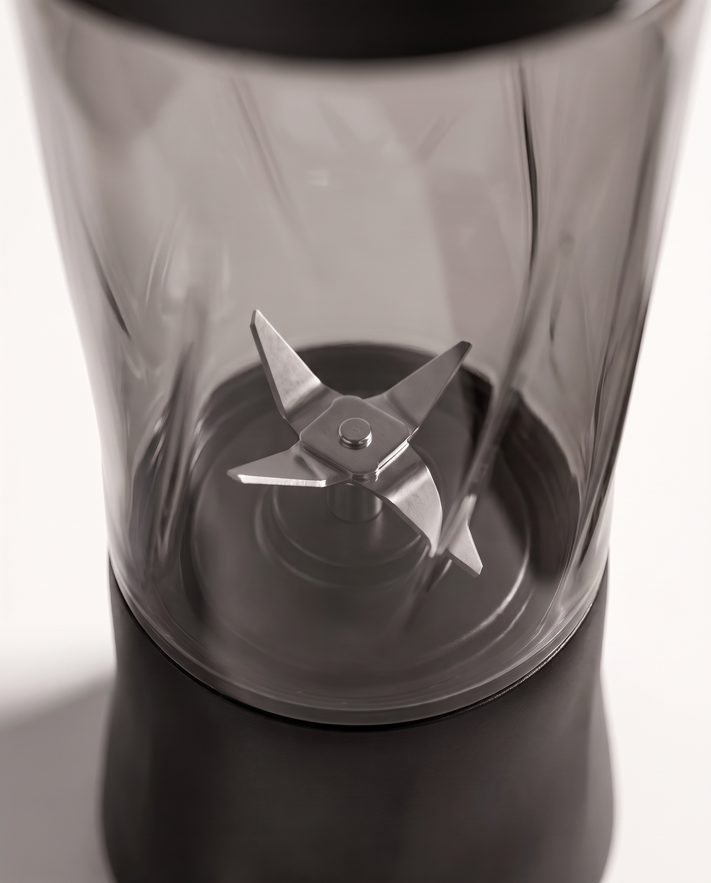 Macro detail of the six-point stainless steel blade assembly seen through the tinted bottle wall