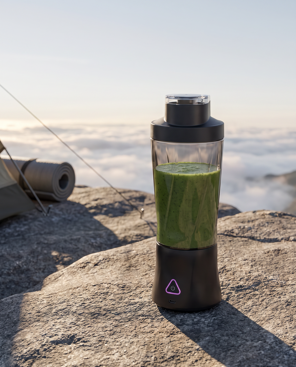 The portable blender on a granite slab above a cloud-filled valley at dawn, filled with a green smoothie