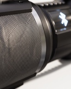Macro detail of the speaker's perforated driver grille and the edge of the lit display panel