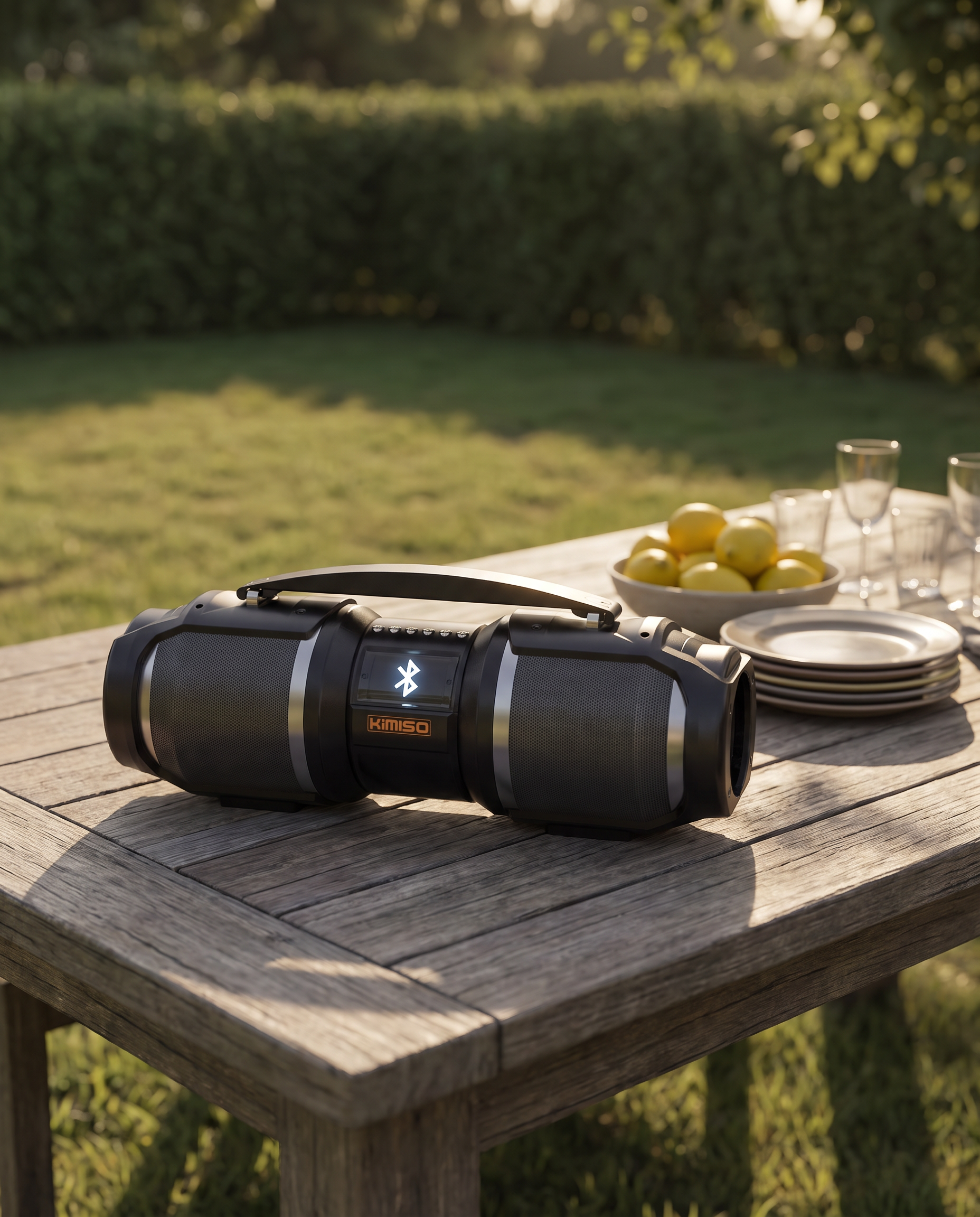 The Bluetooth speaker on a long timber table laid for a garden party in late afternoon sun