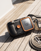 The housing resting on weathered teak decking beside a snorkel mask and a coiled safety rope.