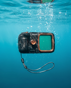 The housing submerged in clear turquoise water, sunlight filtering down through rising bubbles.
