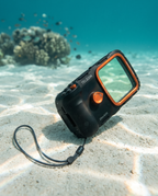 The housing resting on pale sand on a shallow reef floor in clear turquoise water.