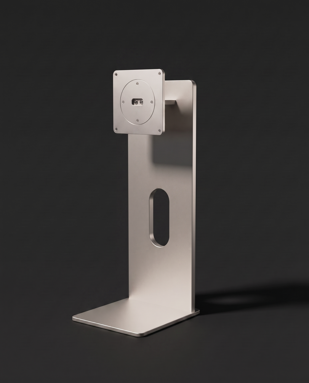 Silver anodised aluminium monitor stand with a weighted base and an oval cable slot cut through the column, shown against a graphite background.
