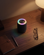 Split speaker half glowing on a walnut desk in a dim room, seen from above